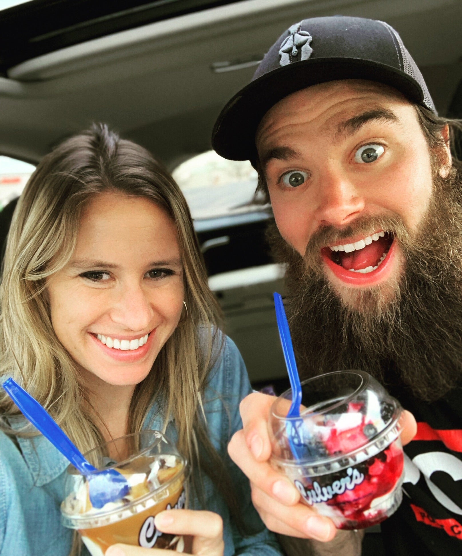 A couple holding sundaes in their car
